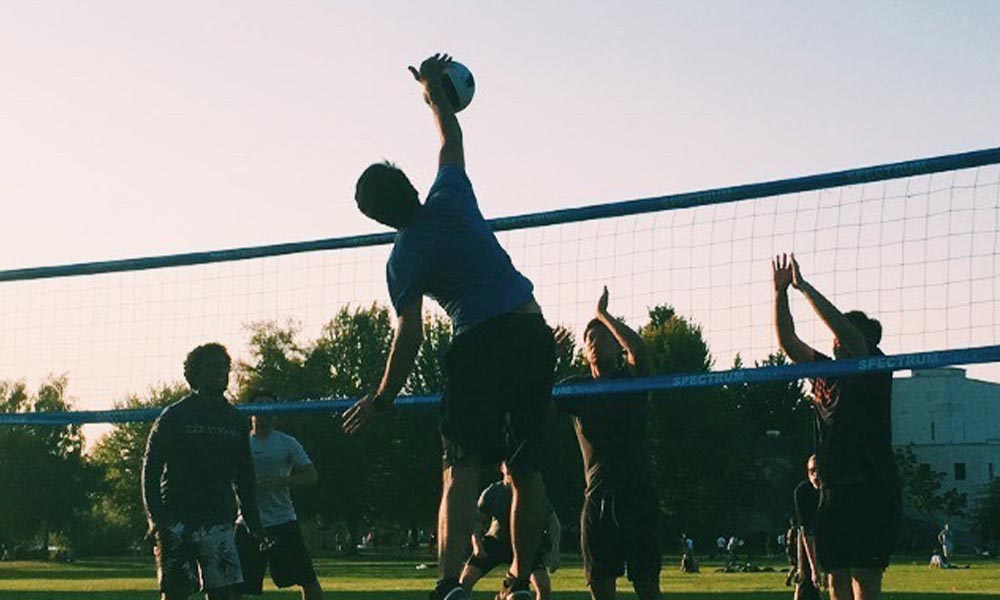 A group of young adults play volleyball at sunset at Green Lake.